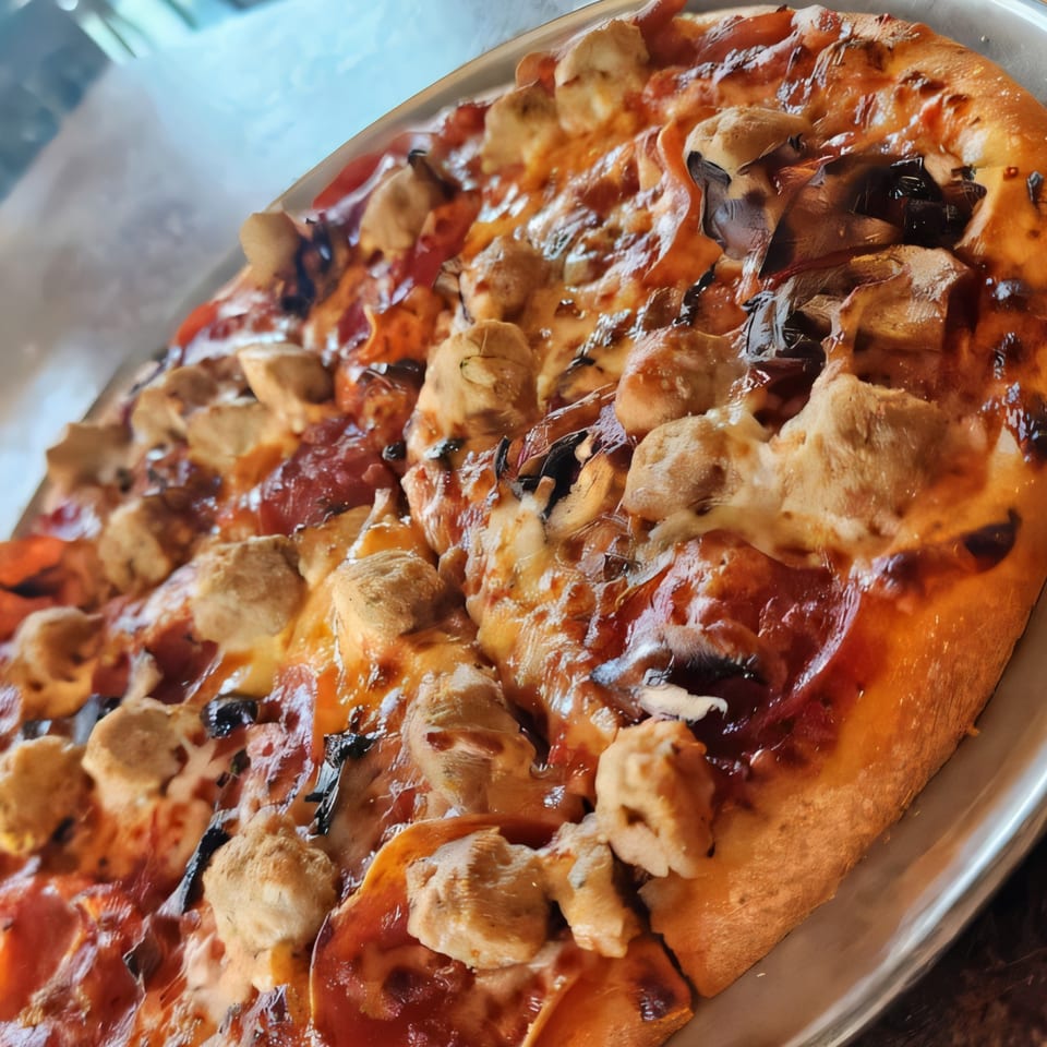 A close-up of a Palio's Pizza Cafe pizza with chicken, mushrooms, and pepperoni.
